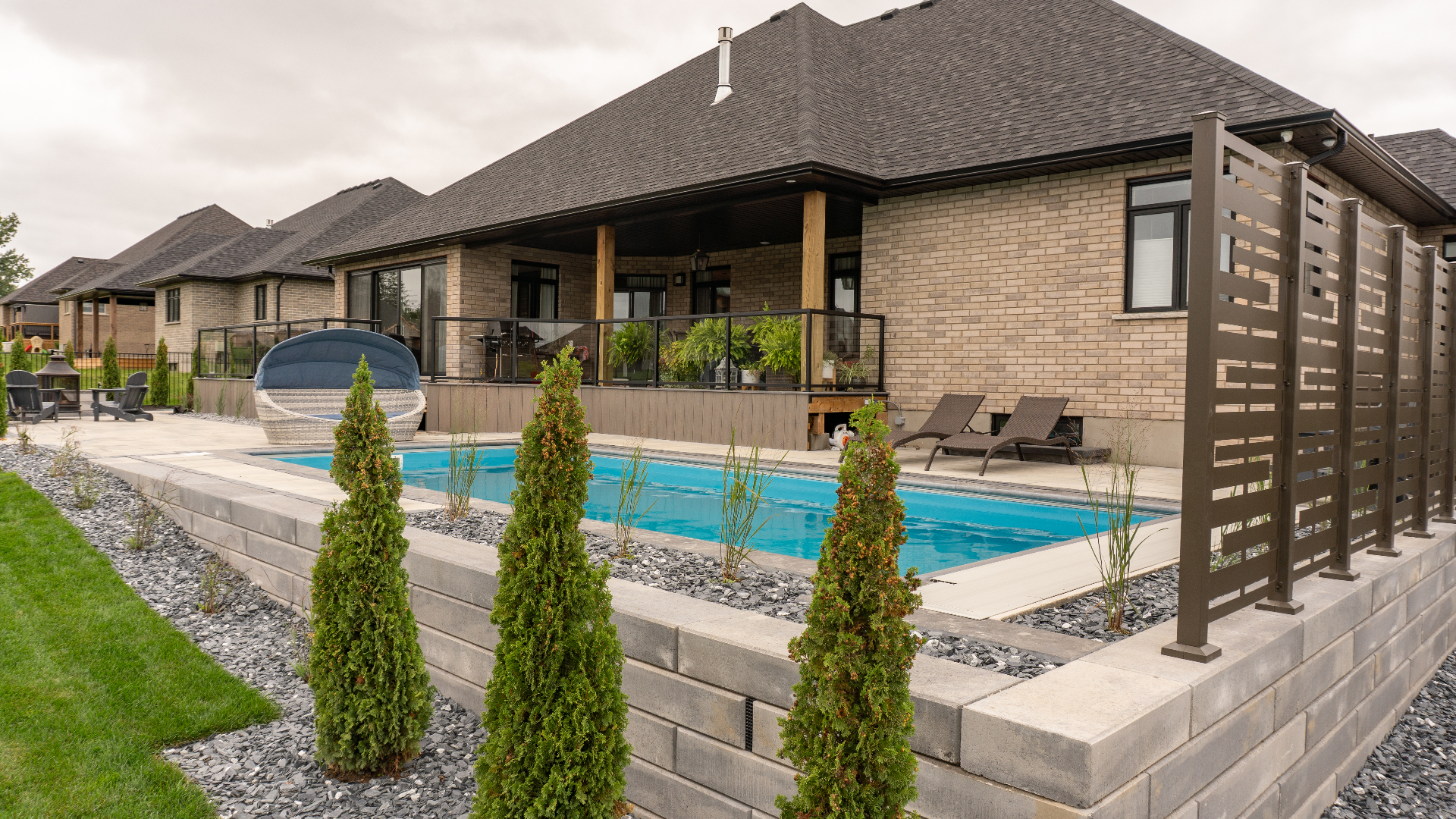 Custom backyard pool with interlock retaining wall and landscaping